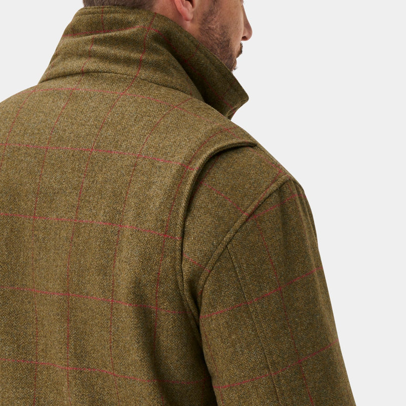 A man shown from the back wearing an olive brown tweed jacket, matching tweed trousers, and a matching flat cap against a light gray studio background.