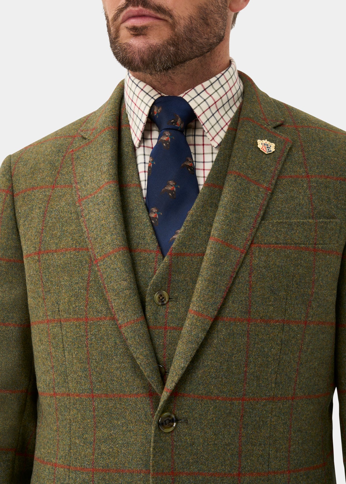 Man wearing Combrook Men’s Tweed Water Repellent Sports Blazer in Reed, plaid shirt, and blue tie with gold lapel pin.