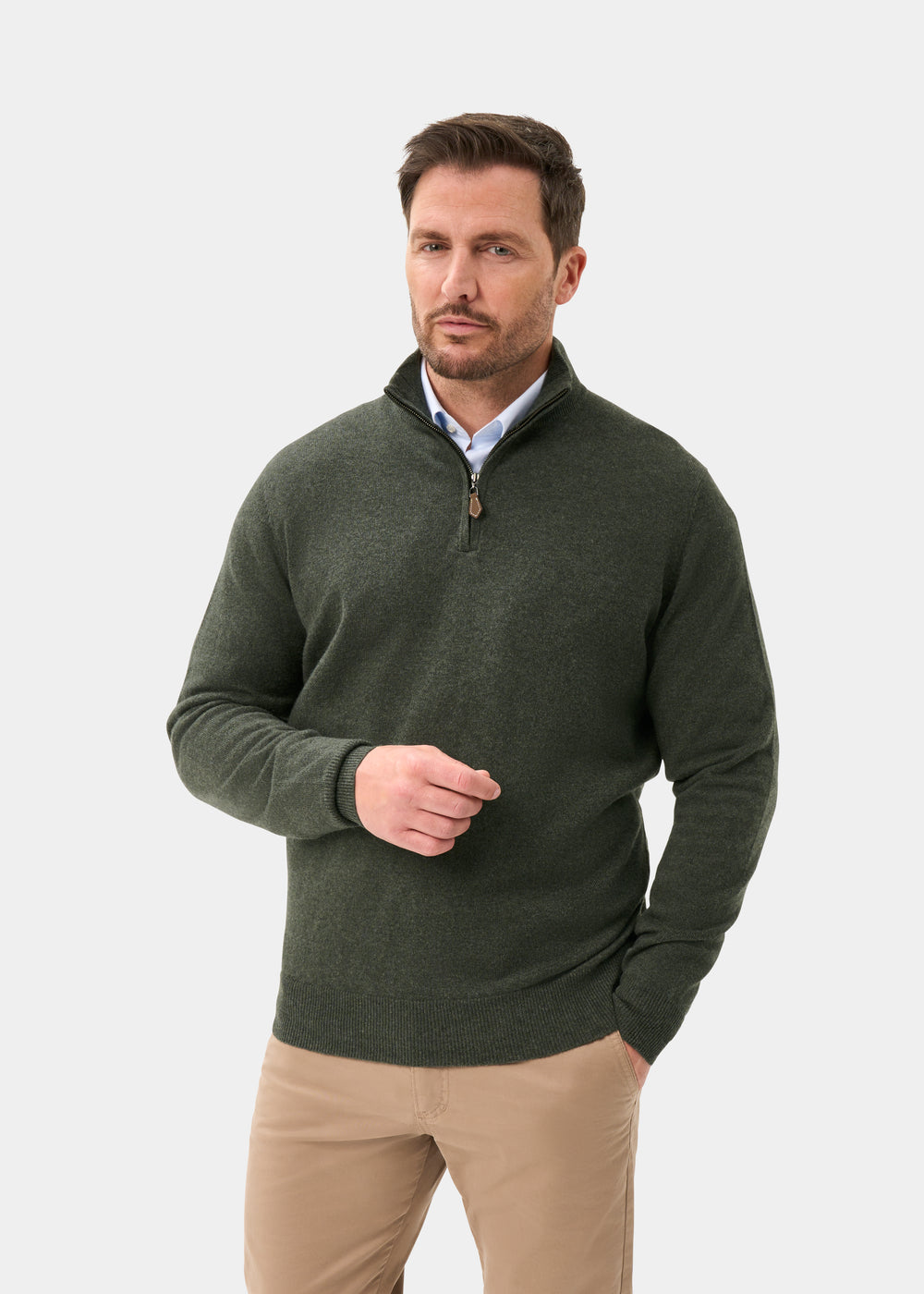 Man in Hanbury Cashmere Quarter Zip Jumper in Rosemary and khaki pants stands against a white background, looking aside.