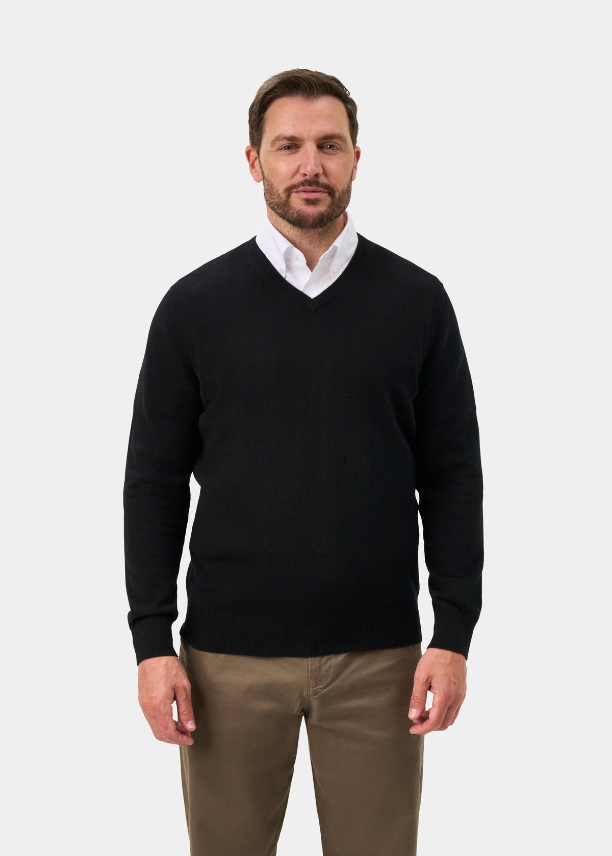 Man in Haddington Pure Cashmere V-Neck Jumper in black, white shirt, and khakis against a plain background.