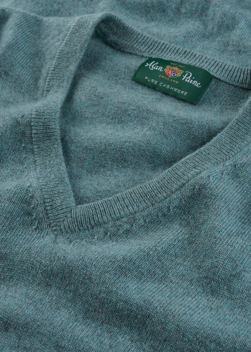 Close-up of the Haddington Pure Cashmere V-Neck Jumper in Caspian with a green Alan Paine label.