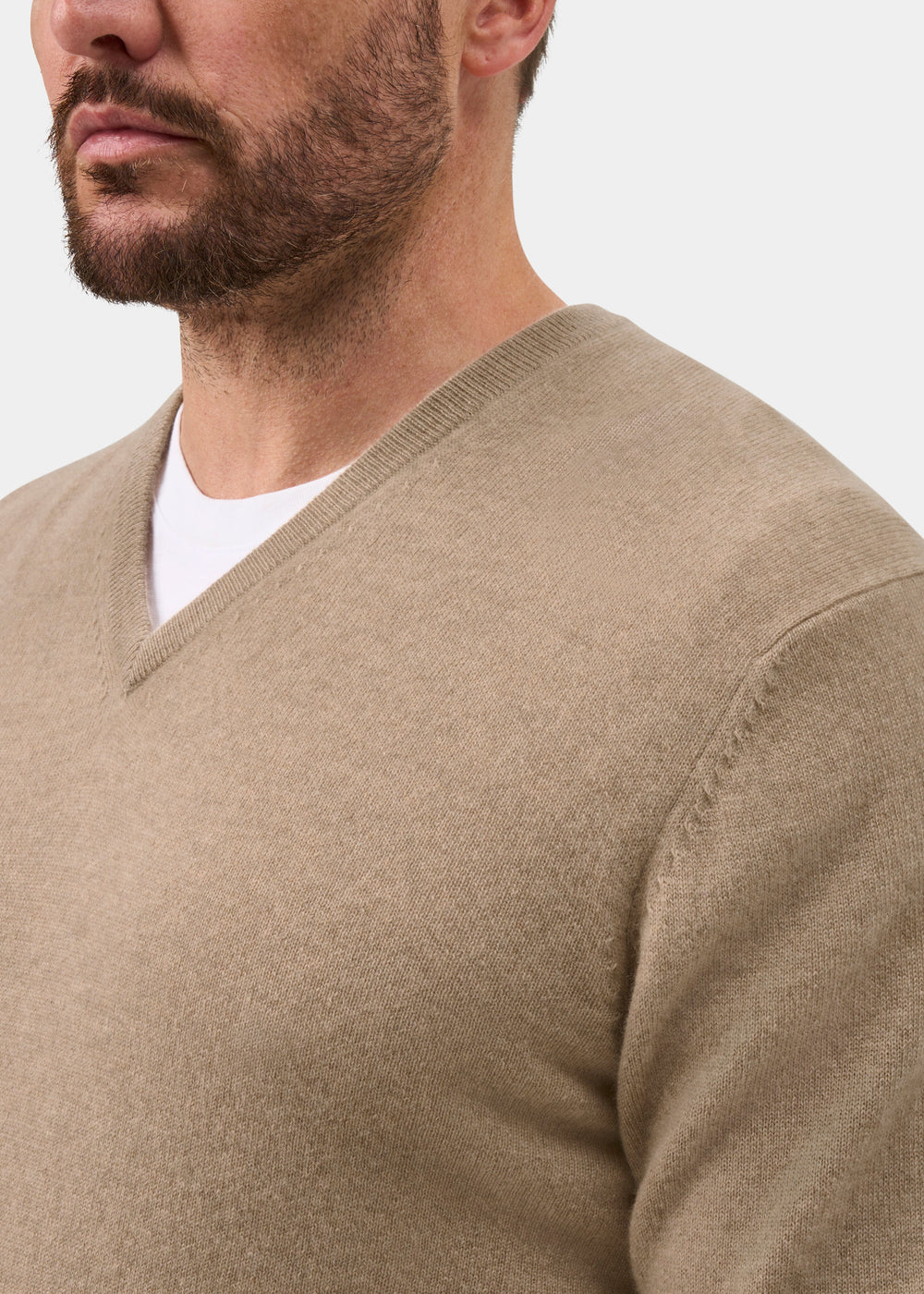 Man wearing Haddington Pure Cashmere V-Neck Jumper in Linen, regular fit, over a white shirt against plain background.