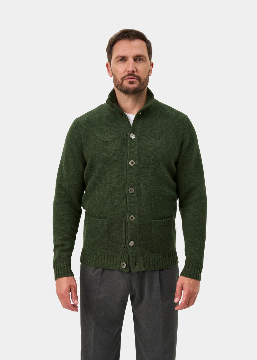 Man wears Landford Rosemary lambswool mock neck jumper over a white shirt and gray pants, against a plain background.