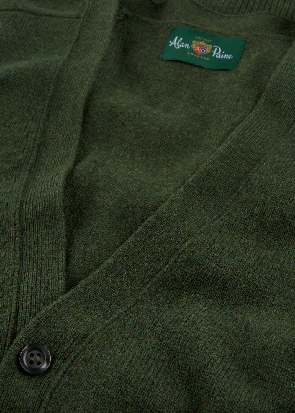 Close-up of the Cornwall Lambswool V-Neck Cardigan in Rosemary with black button and Alan Paine London label inside collar.