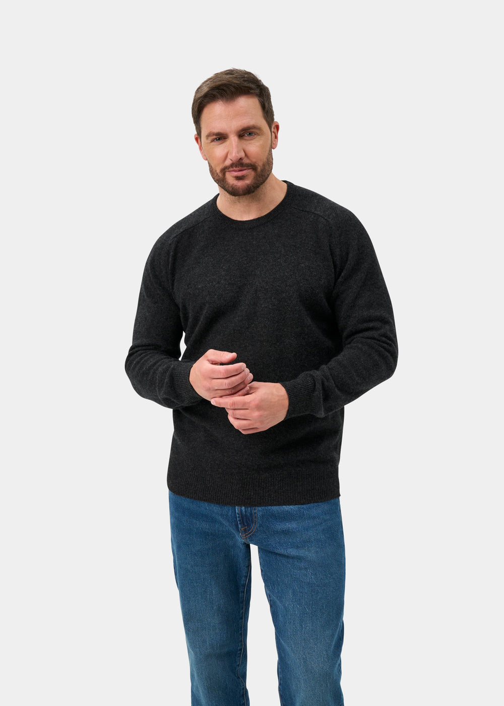 Man with short brown hair and beard wears Dorset Lambswool Crew Neck Jumper in Charcoal - Classic Fit, plus blue jeans.