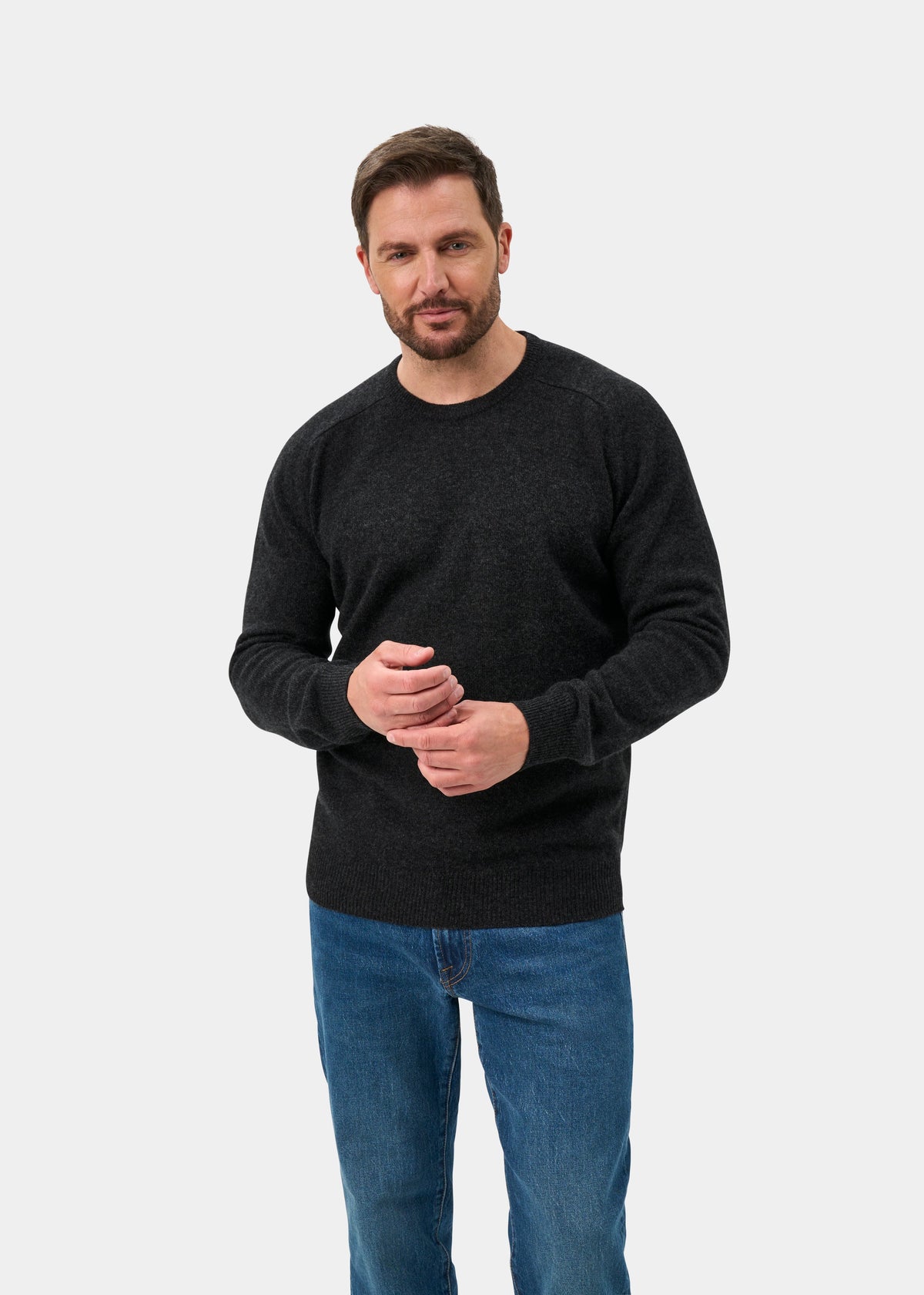 Man with short brown hair and beard wears Dorset Lambswool Crew Neck Jumper in Charcoal - Classic Fit, plus blue jeans.