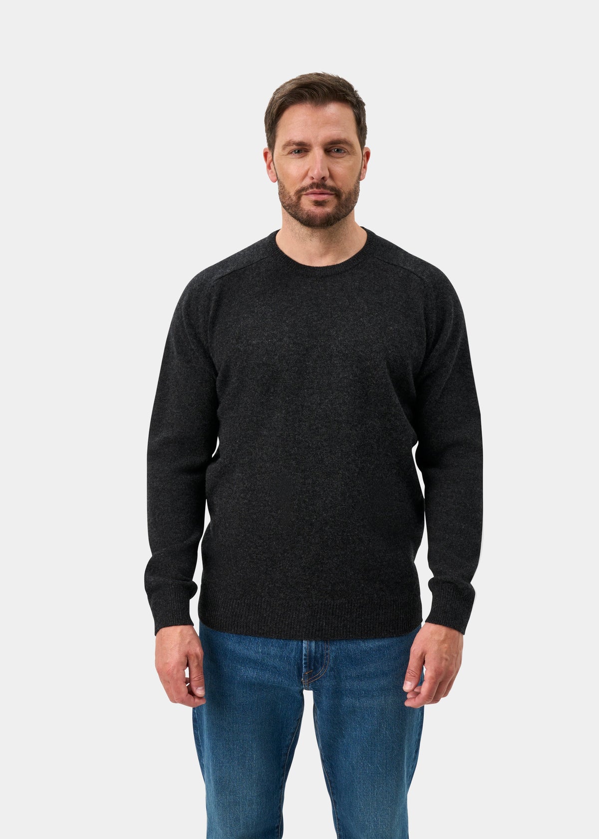 Man with short brown hair wears Dorset Lambswool Crew Neck Jumper in Charcoal, classic fit, against a light backdrop.