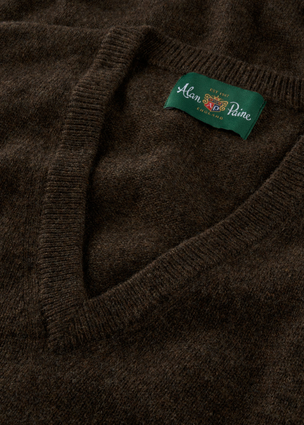 Close-up of a dark brown sweater with a brand label on the collar.