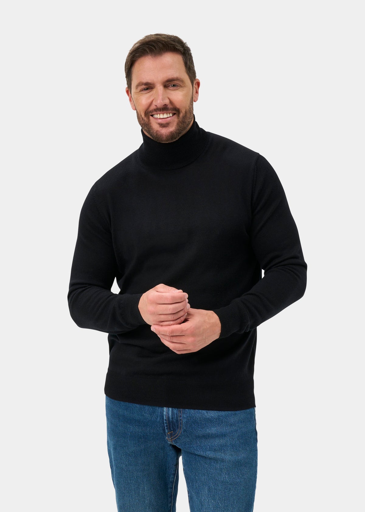 Man in Linton Merino Wool Roll Neck Jumper in black, regular fit, and blue jeans against a plain background.