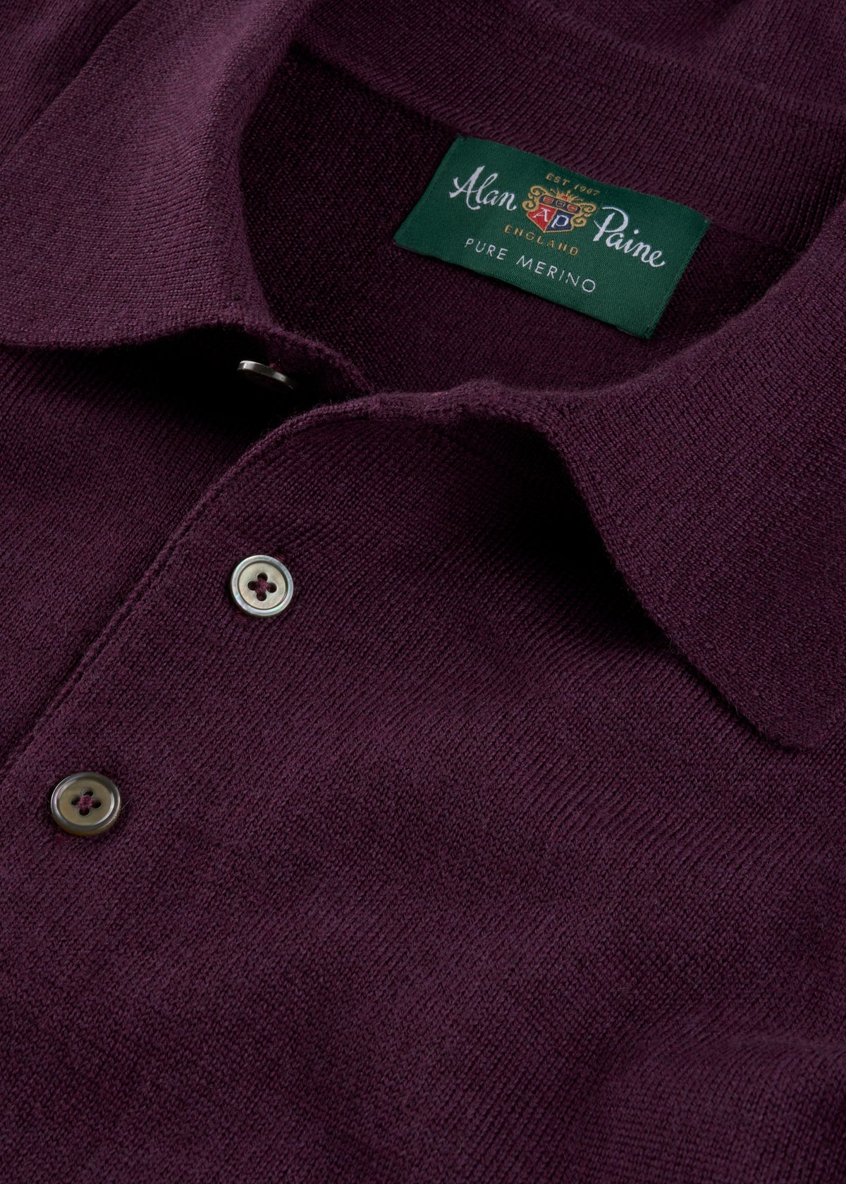 Close-up of the Hindhead Men’s Merino Wool Polo Shirt in Black Grape, showing buttons and inside collar label.