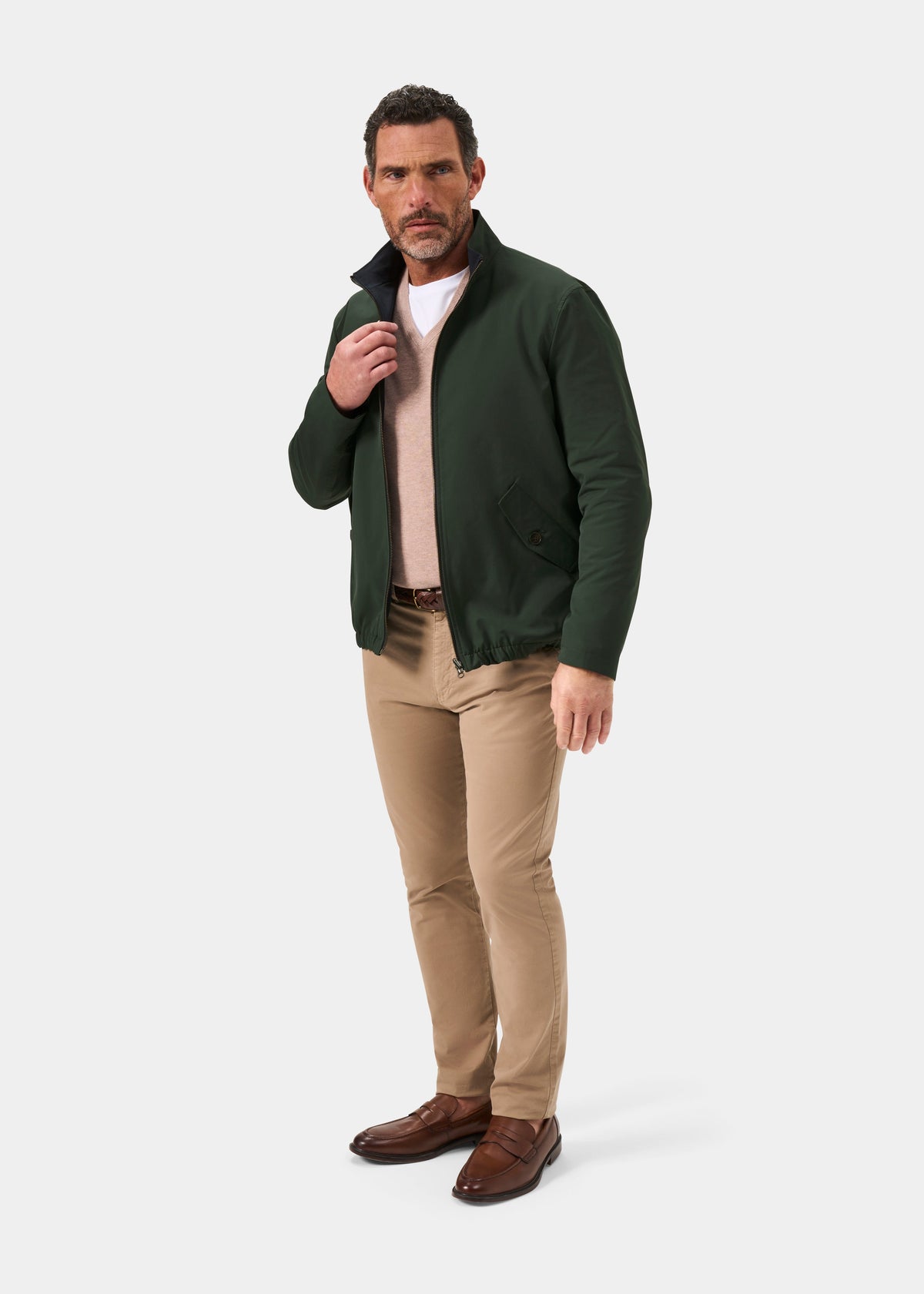 Man in Lakeward Men’s Reversible Bomber Jacket (Green/Navy), beige sweater, tan pants, brown shoes on white backdrop.