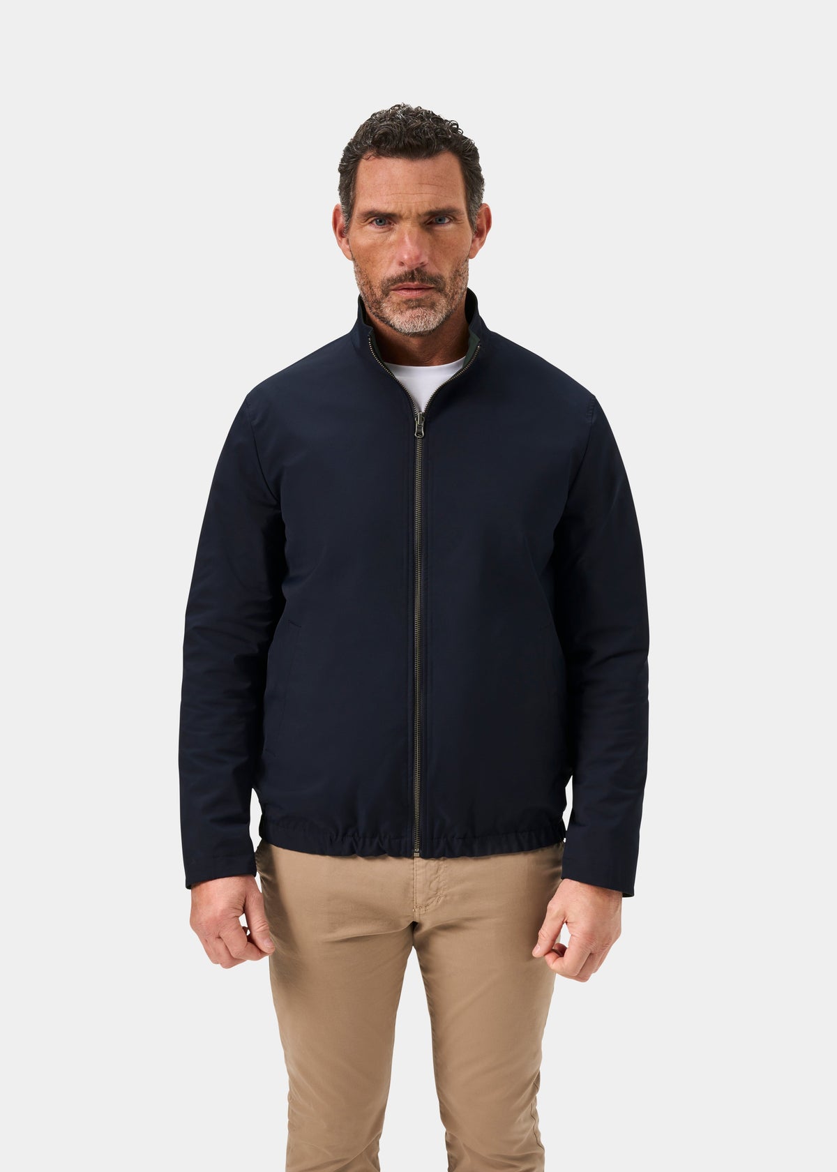 Man in a Lakeward Men’s Reversible Bomber Jacket in Green and Navy, with beige pants, stands facing forward.