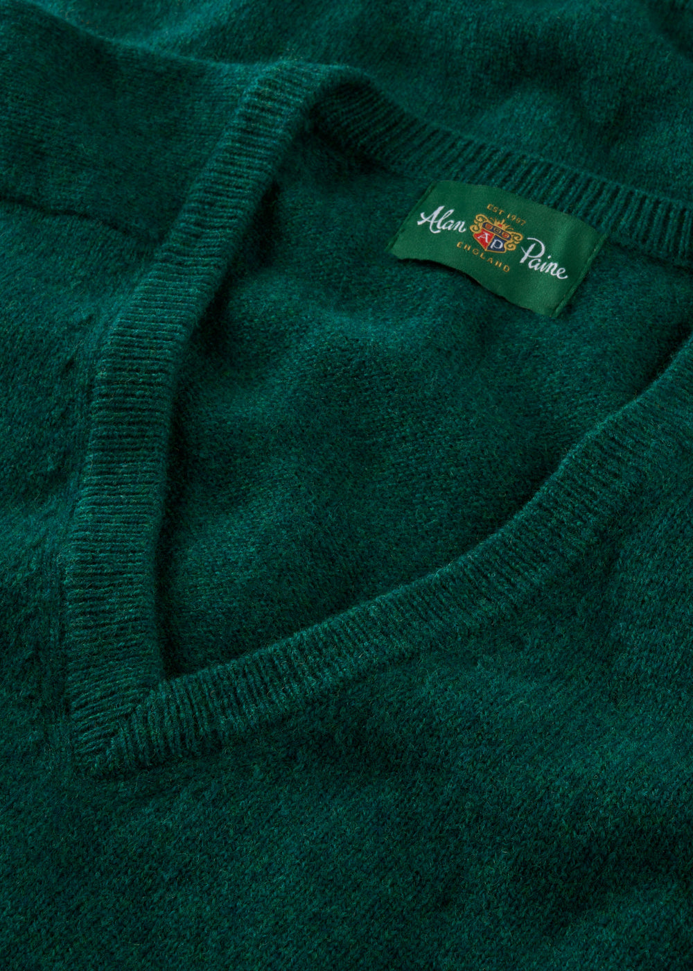 Close-up of Hampshire Lambswool V-Neck Jumper in Mallard, classic fit, featuring saddle shoulder and Alan Paine label.