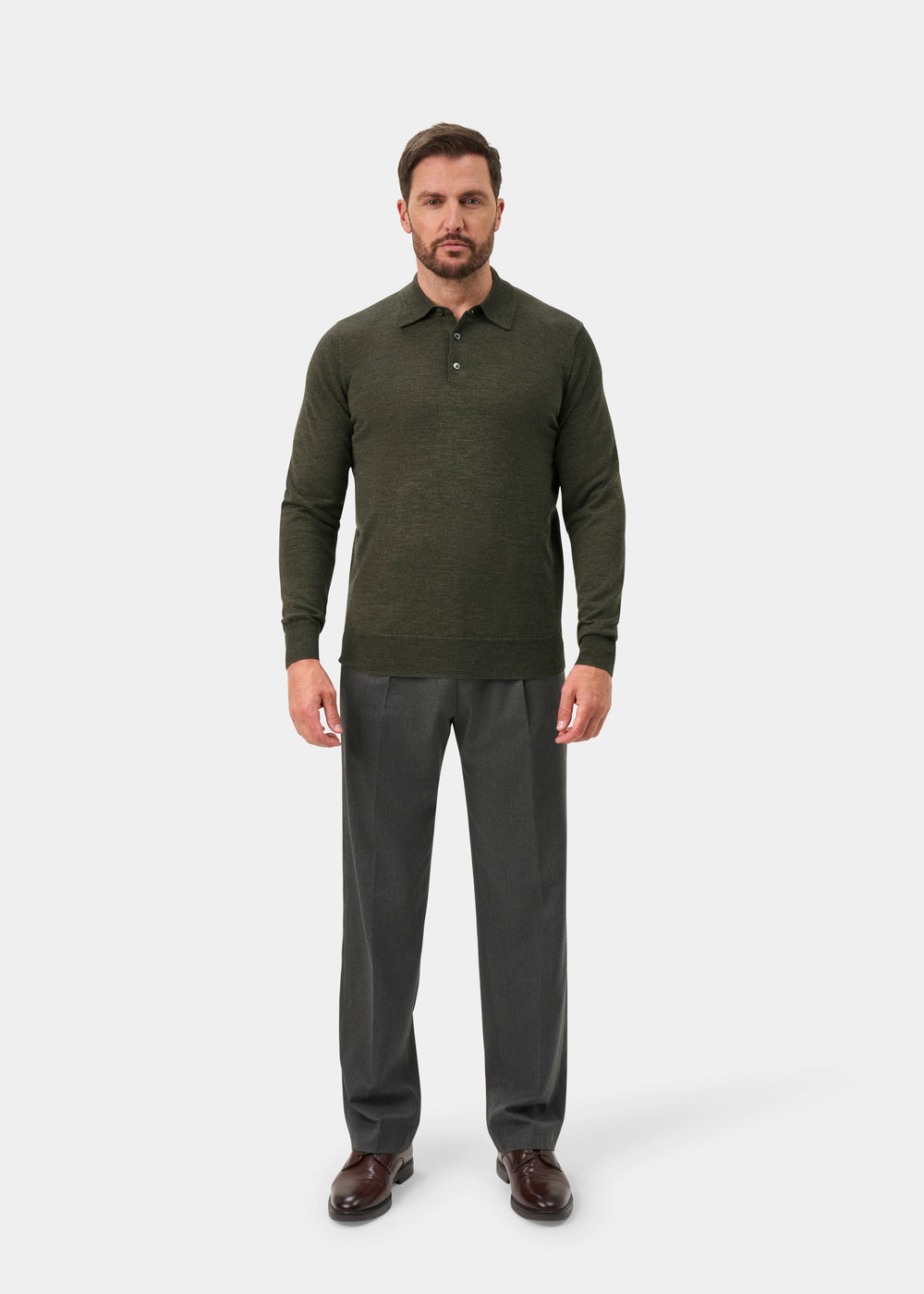 Man in Hindhead Seaweed Merino Wool Polo Shirt, regular fit; gray trousers, standing against a white background.