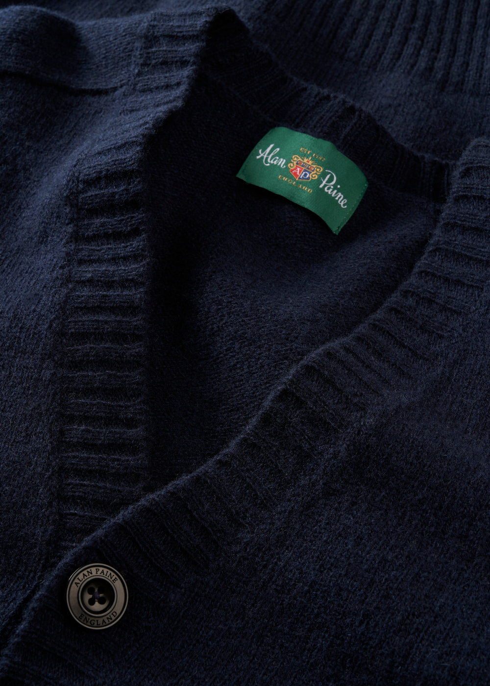 Close-up of Kinloch Supersoft Shetland Wool V-Neck Cardigan in Concord with button and green Alan Paine label.