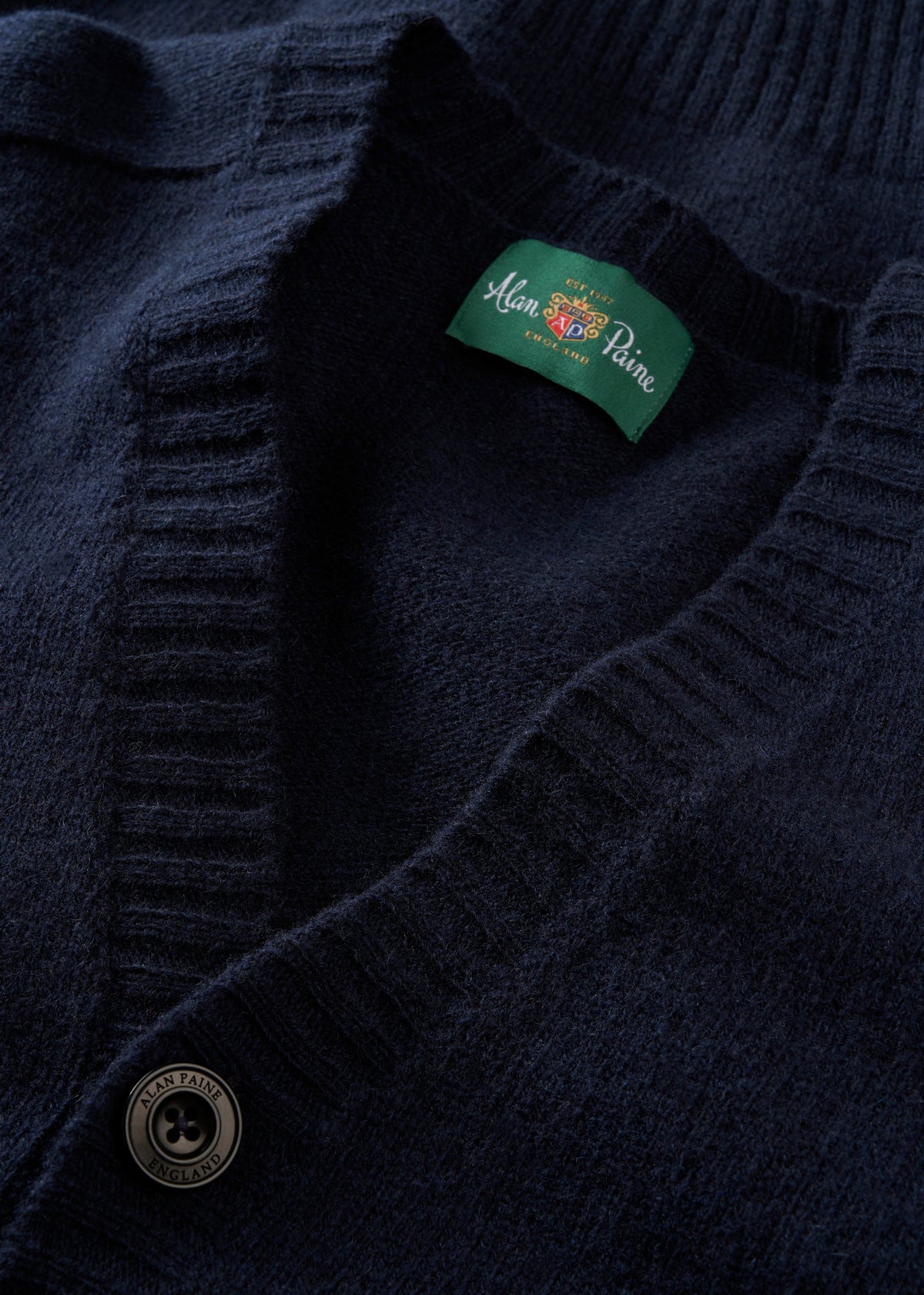 Close-up of Kinloch Supersoft Shetland Wool V-Neck Cardigan in Concord with button and green Alan Paine label.