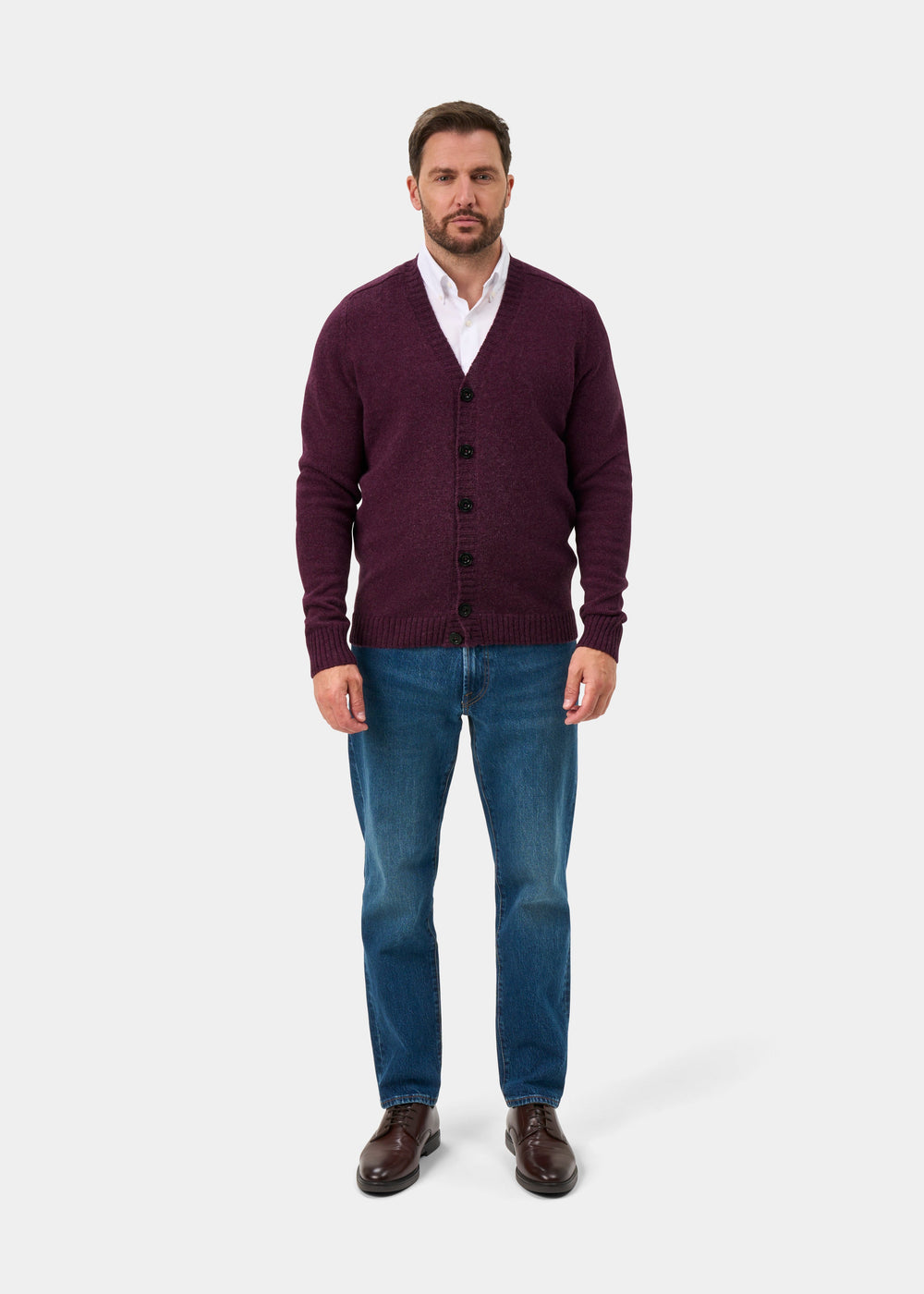 Man in a Kinloch Elderberry Supersoft Shetland Wool V-Neck Cardigan, white shirt, and blue jeans faces forward.