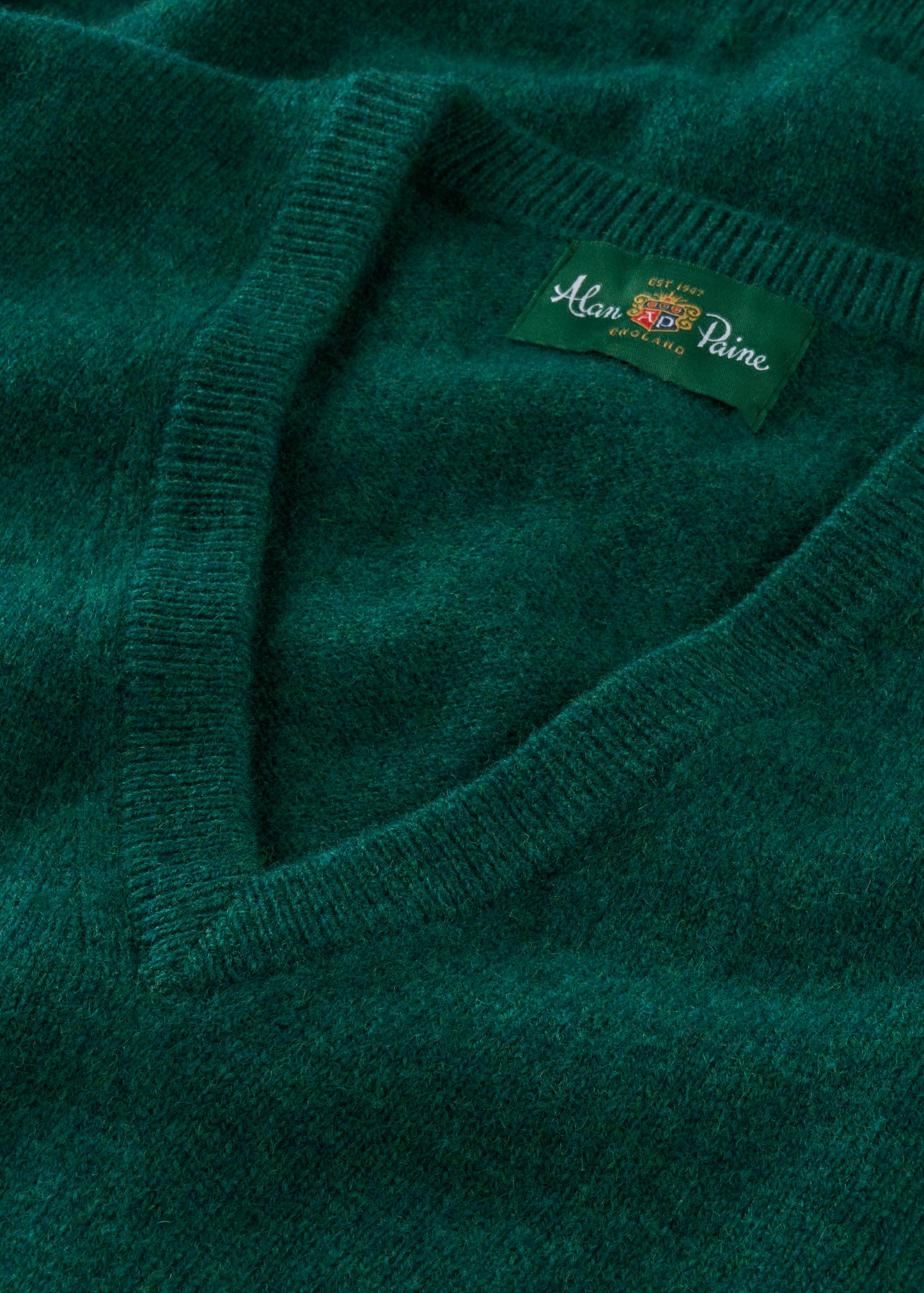 Close-up of a green sweater with a brand label on a matching background