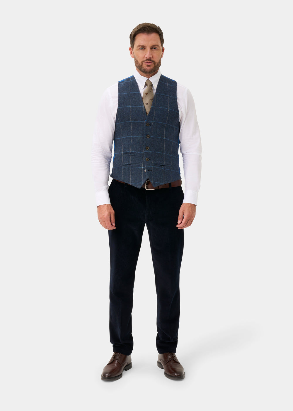 A man wearing a Surrey Men’s Tweed Water Repellent Lined Waistcoat in Midnight Blue, white shirt, tie, and trousers.