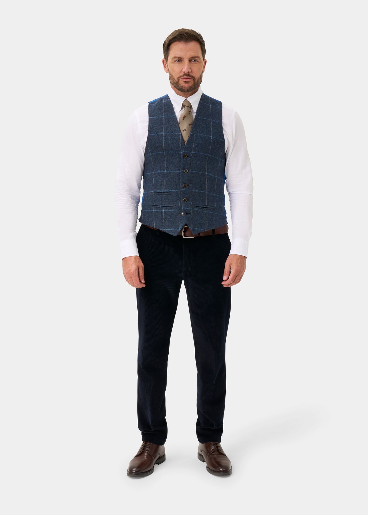 A man wearing a Surrey Men’s Tweed Water Repellent Lined Waistcoat in Midnight Blue, white shirt, tie, and trousers.