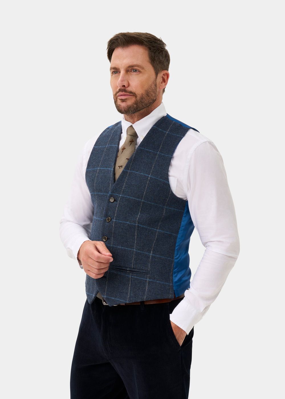 A man wears a Surrey Men’s Tweed Water Repellent Lined Waistcoat in Midnight Blue over a white dress shirt and tie.