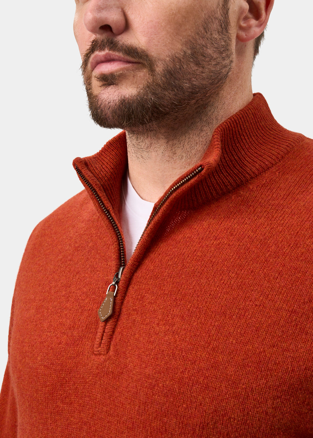 A man wearing a Sutherland Lambswool Quarter Zip Jumper In Ember over a white crew-neck shirt.