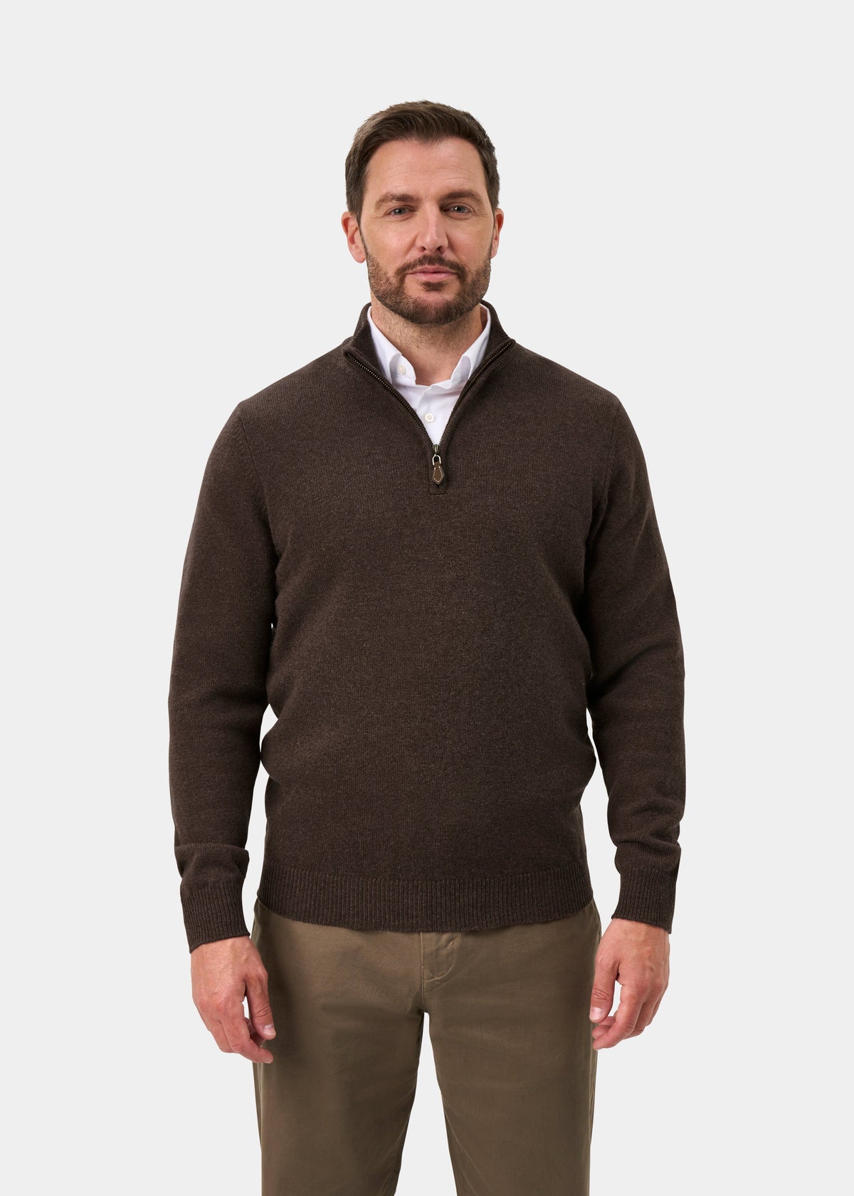 A man wearing a Sutherland Lambswool Quarter Zip Jumper In Mocha over a white collared shirt and khaki trousers.